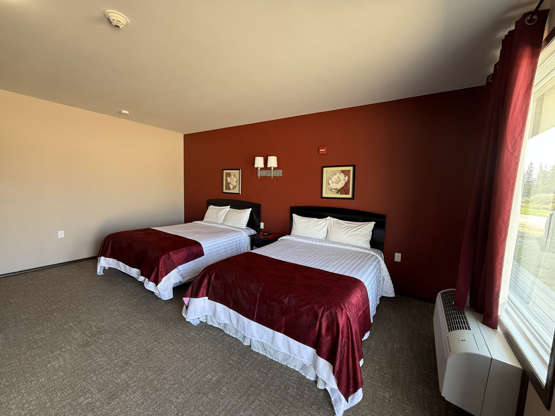 Two queen beds with bedside lighting in a Moosehorn Motor Hotel room