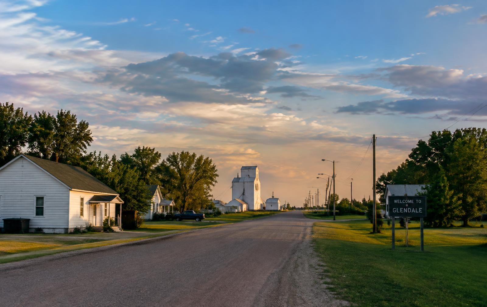 Quiet rural prairie village street with a grain elevator in the distance